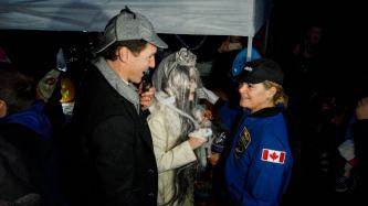 PM Trudeau and Sophie in costume speak with a woman