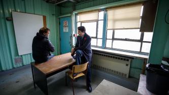 PM Trudeau and Mayor Spence sit on a table and speak