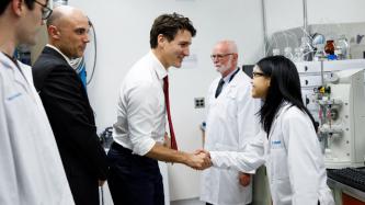 PM Trudeau shakes hands with a woman in a lab coat