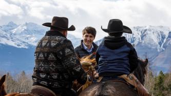 Le PM Trudeau, assis sur un cheval, parle à des personnes autochtones