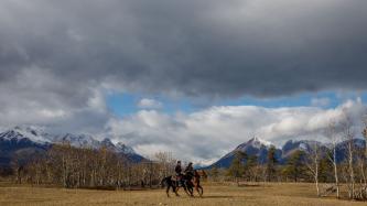 Le PM Trudeau et un homme autochtone se promènent à cheval dans une vallée