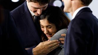 PM Trudeau hugs a woman while President Macron looks on