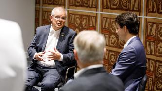 PM Trudeau sits and listens to PM Scott Morrison