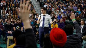 Attendees raise their hands as PM Trudeau speaks