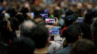 Members of the audience take photos with their cellphones