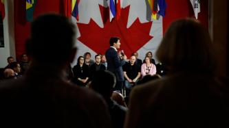 PM Trudeau holds a microphone and speaks to the crowd