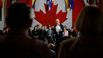 MP Finnigan holds a microphone and speaks to the crowd