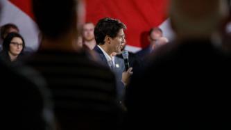 PM Trudeau holds a microphone and speaks to the crowd
