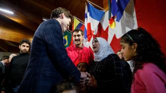 PM Trudeau shakes hands with a woman while her family looks on