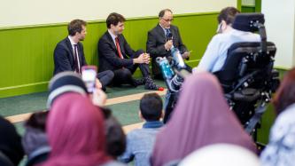 PM Trudeau and MP Lightbound sit and listen to a man speak