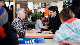 Le PM Trudeau est assis et parle à un client
