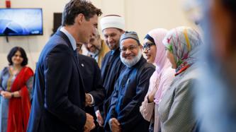 PM Trudeau speaks to a woman while others look on