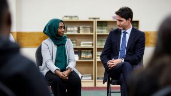 PM Trudeau sits and listens to a woman speak