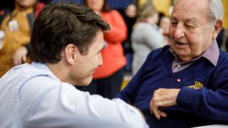 PM Trudeau kneels and speaks with a resident