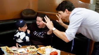 Le PM Trudeau fait des gestes et sourit à un jeune garçon et à la femme qui le tient