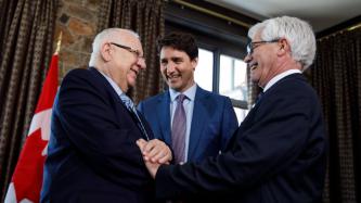 President Rivlin shakes hands with Minister Carr while PM Trudeau looks on