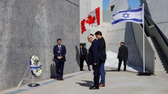 PM Trudeau and President Rivlin bow facing a memorial wreath