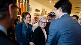 PM Trudeau shakes hands with a woman while others look on