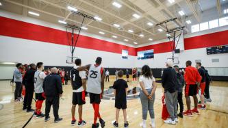 Clinic attendees stand in a circle in a gymnasium