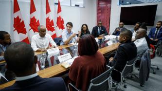 PM Trudeau and Minister Hussen sit in a meeting with business leaders