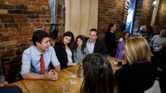 PM Trudeau sits and speaks with a family
