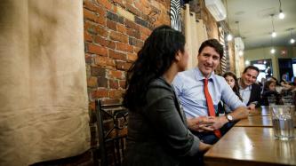 PM Trudeau sits and speaks with a woman