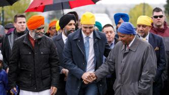 Le PM Trudeau serre la main d’un homme sous le regard du ministre Sajjan et d’autres personnes