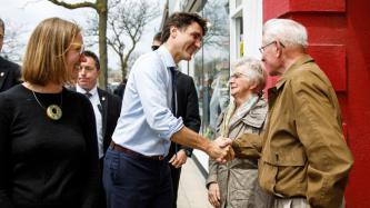 PM Trudeau shakes hands with an elderly man beside Minister Gould and an elderly woman