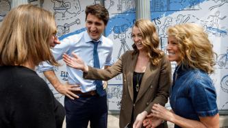 Minister Gould and PM Trudeau smile and speak to two women