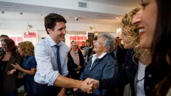 PM Trudeau shakes hands with a woman beside other attendees 