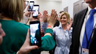 President Kolinda Grabar-Kitarović high fives a woman while others take photos