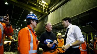 PM Trudeau stands speaking with a couple of steel workers