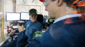 Le PM Trudeau porte des lunettes de sûreté et discute avec des employés de l’Aluminerie Alouette
