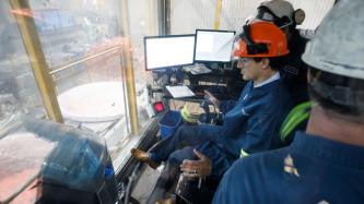 Le PM Trudeau est assis dans une salle de contrôle avec des employés de l’Aluminerie Alouette