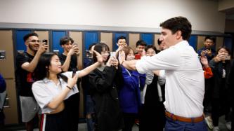 Le PM Trudeau tape dans la main un groupe d’élèves qui prend des photos