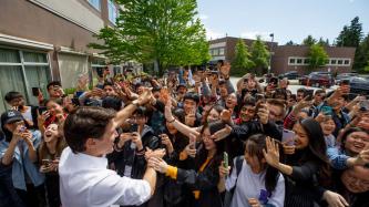 Le PM Trudeau tape dans la main un groupe d’élèves qui prend des photos