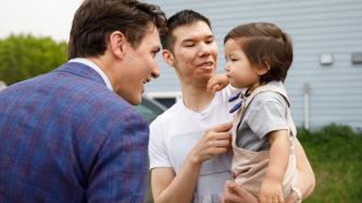PM Trudeau smiles at a child held by a man