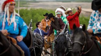 PM Trudeau shakes hands with a man on horseback