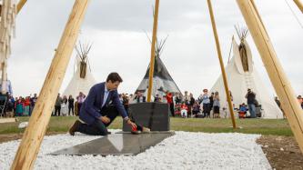 PM Trudeau lays a flower on the grave of Chief Poundmaker