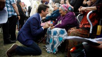 PM Trudeau kneels and shares a laugh with an elderly woman