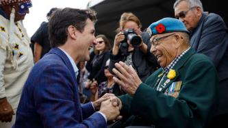 PM Trudeau kneels and shares a laugh with an elderly veteran