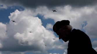 A silhouette of a veteran under a cloudy sky with planes