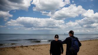 A man accompanies a veteran on the shore