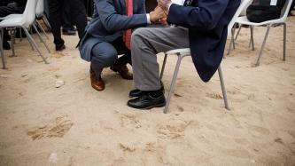 PM Trudeau crouches and holds the hand of a veteran
