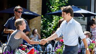 PM Trudeau shakes hands with a woman on an outdoor patio