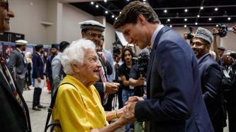 PM Trudeau holds hands with an elderly woman