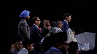 PM Trudeau stands at a podium with others on stage
