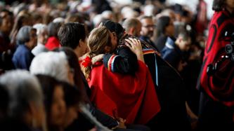 Sophie Grégoire Trudeau hugs a woman while PM Trudeau looks on