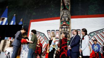 A man and a woman give a garment to PM Trudeau