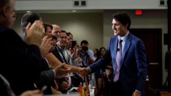 PM Trudeau shakes hands with a woman in line